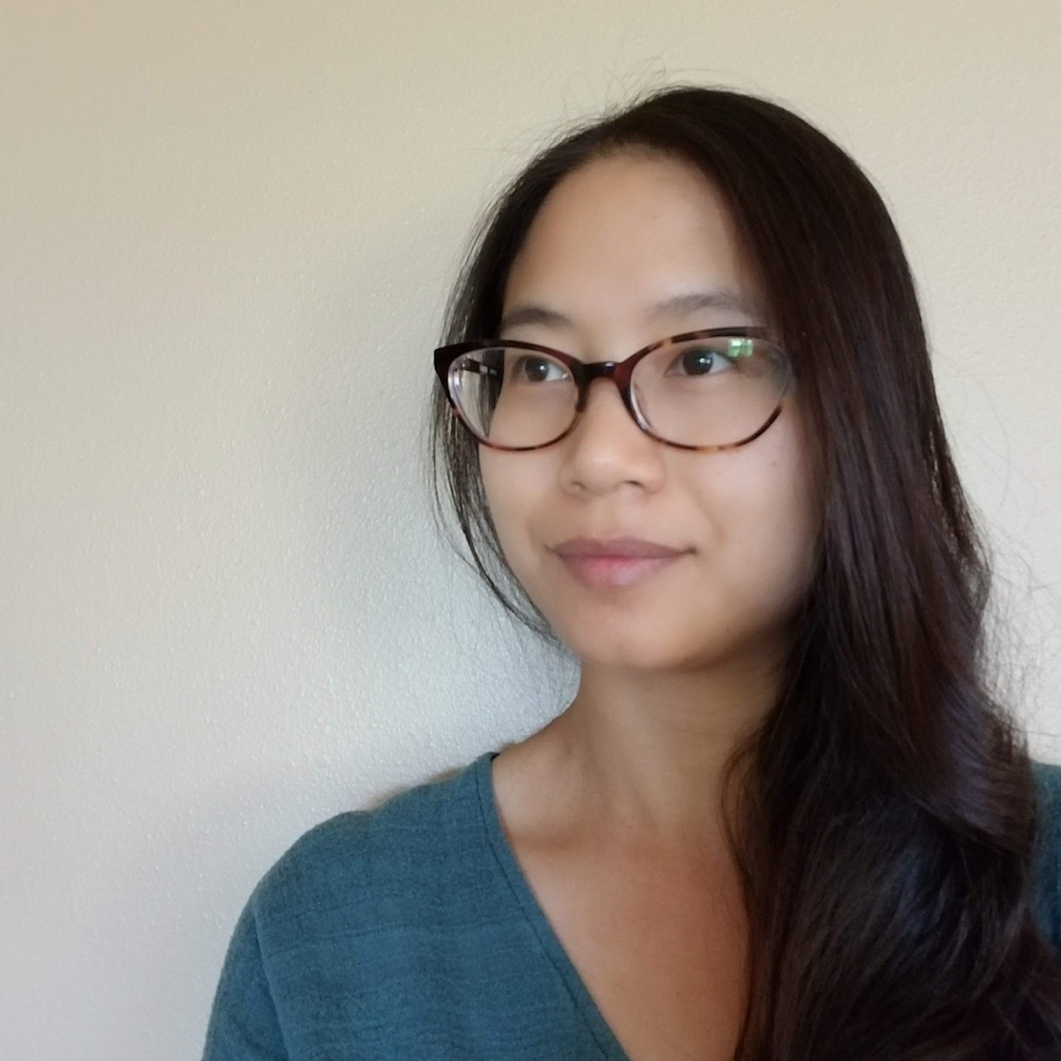 Photo of the artist. Asian decent with long black hair and wearing glasses.