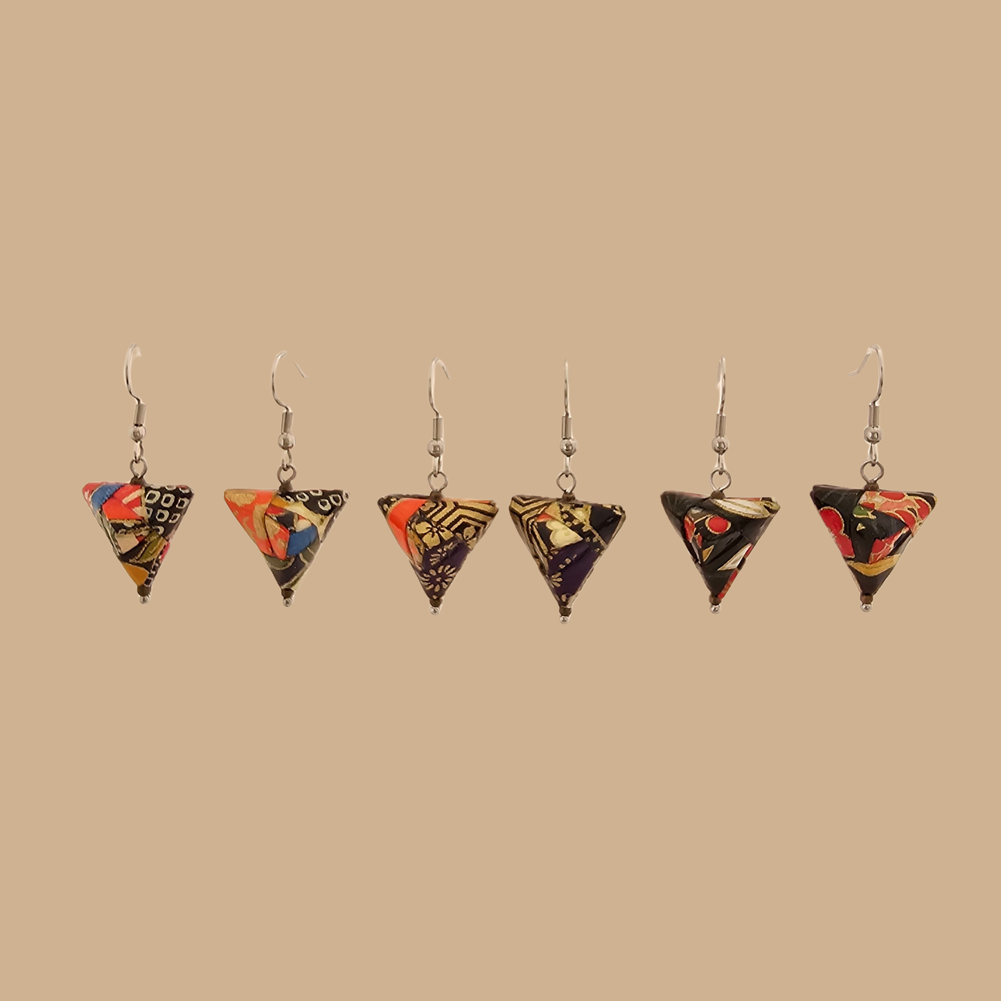 Various pairs of Black and gold geometric origami earrings with a floral pattern on a beige background.