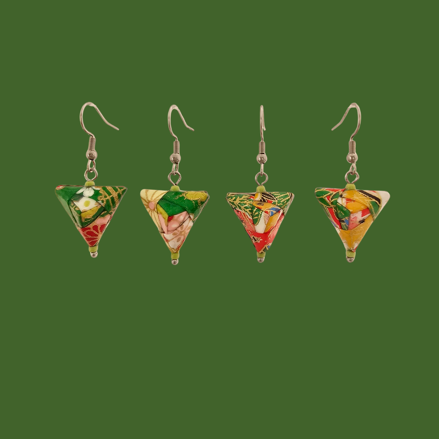 Green, red, and gold geometric origami earrings with a floral pattern on a green background.
