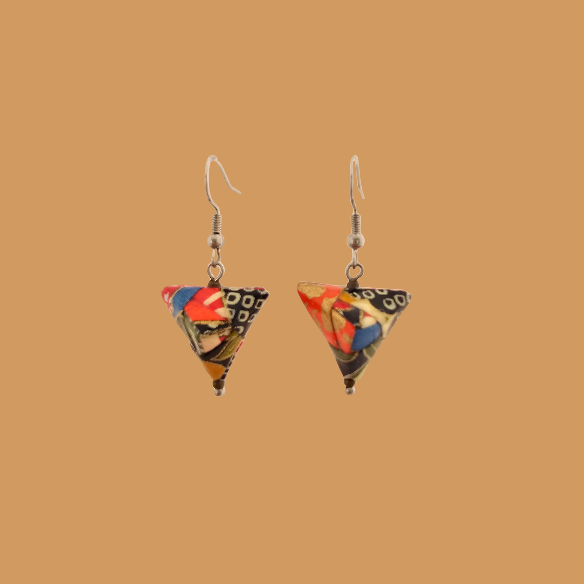 Pair of black, orange, and gold geometric origami earrings with a floral pattern on a beige background.