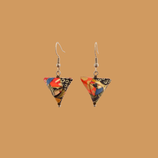 Pair of black, orange, and gold geometric origami earrings with a floral pattern on a beige background.