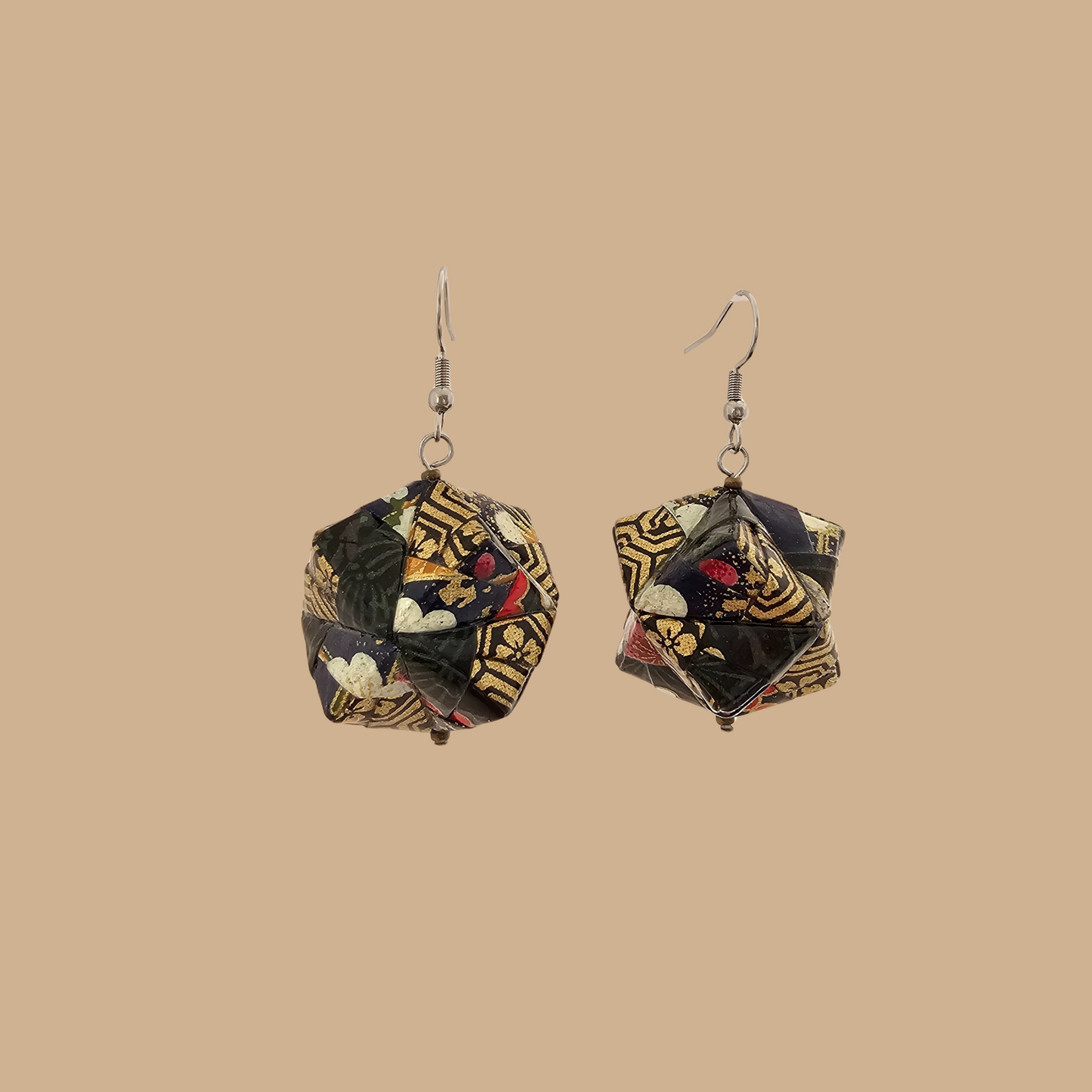 Pair of black and gold geometric origami earrings with a floral pattern on a beige background.