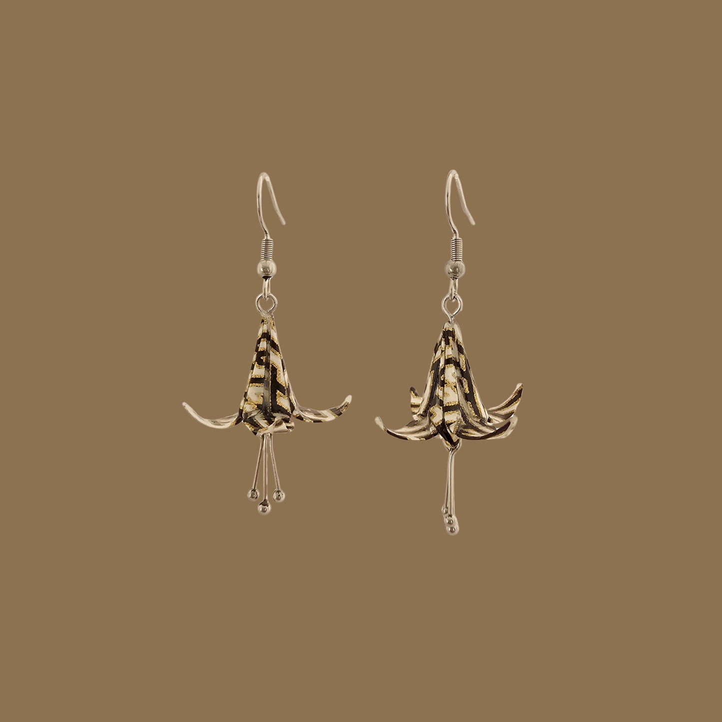 Black and gold origami lily earrings with a floral and geometric pattern on a beige background
