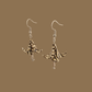Black and gold origami lily earrings with a floral and geometric pattern on a beige background