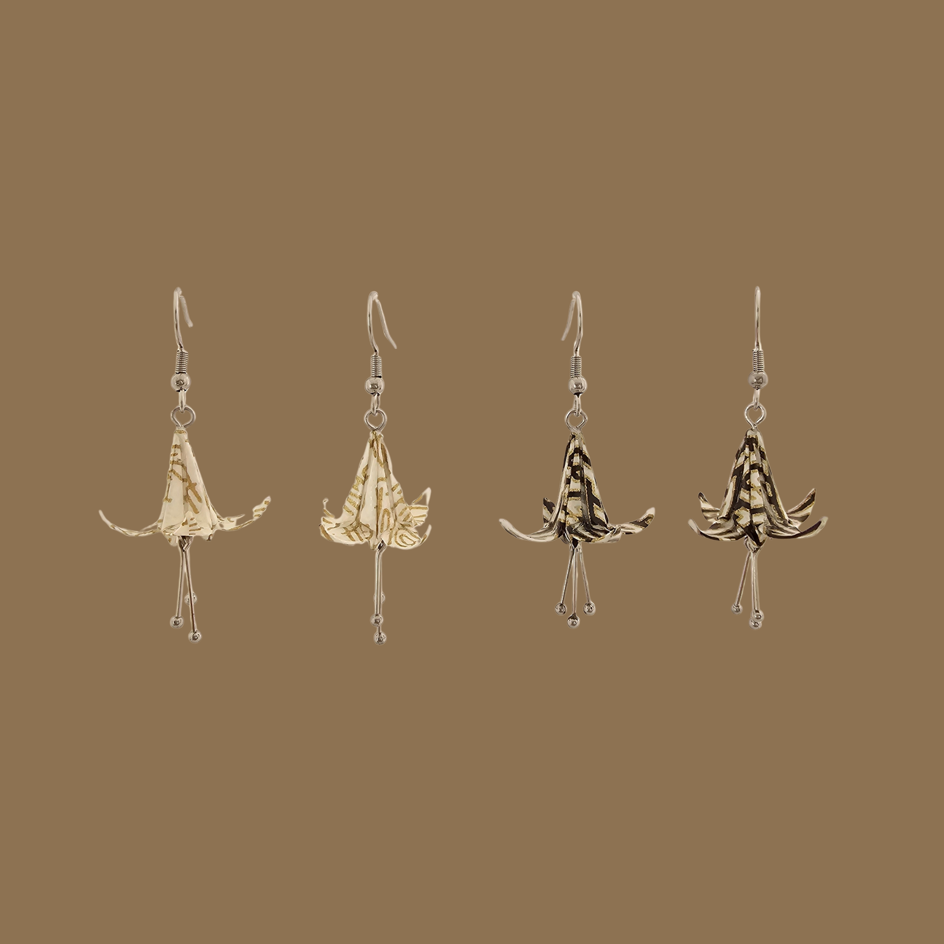 Two pairs of white and black origami lily earrings with a floral and geometric pattern on a beige background