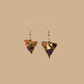 Black and gold geometric origami earrings with a floral pattern on a beige background.