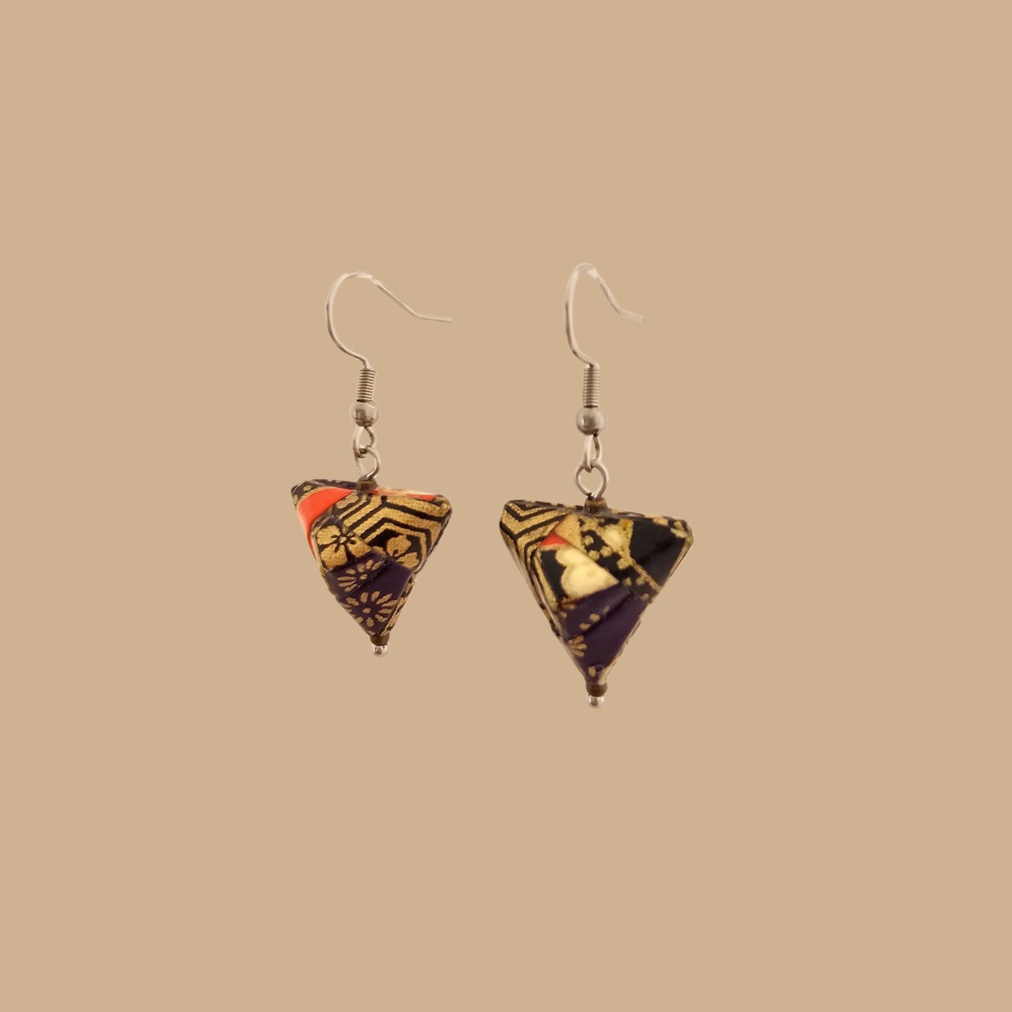 Black and gold geometric origami earrings with a floral pattern on a beige background.