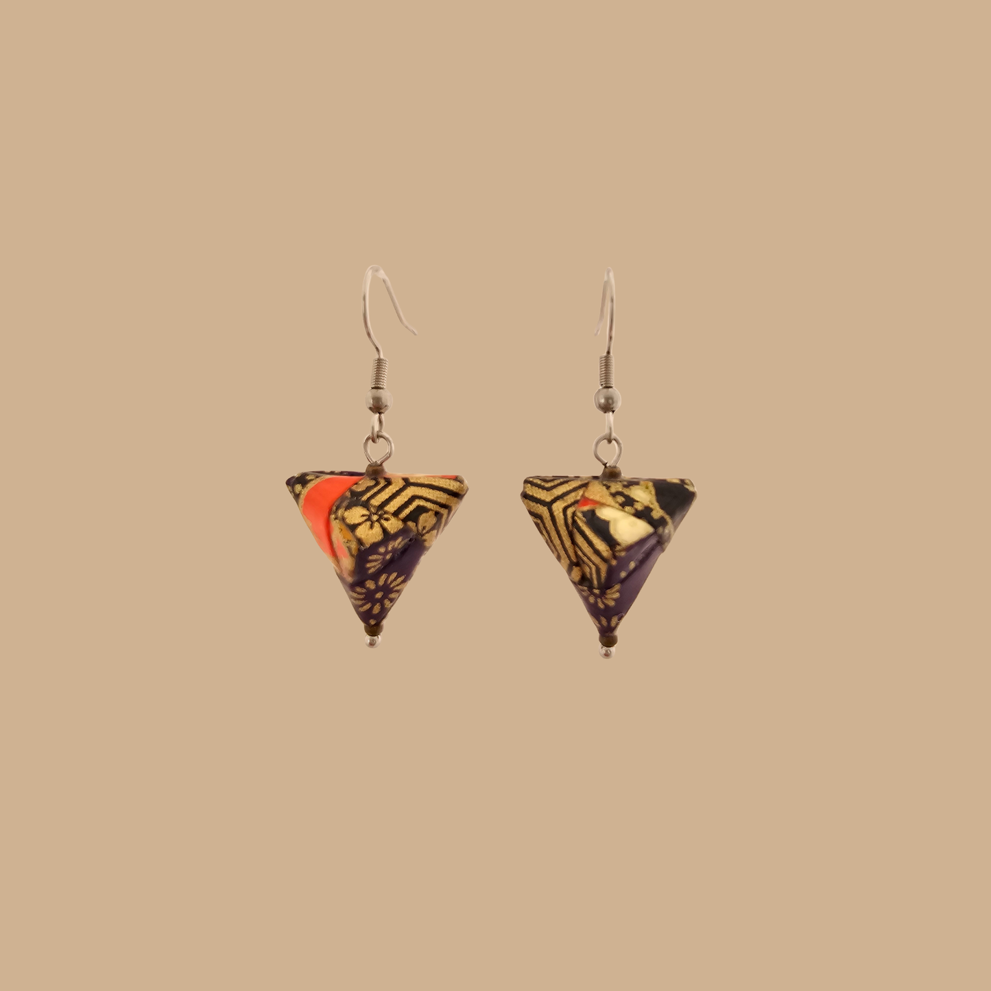 Black and gold geometric origami earrings with a floral pattern on a beige background.