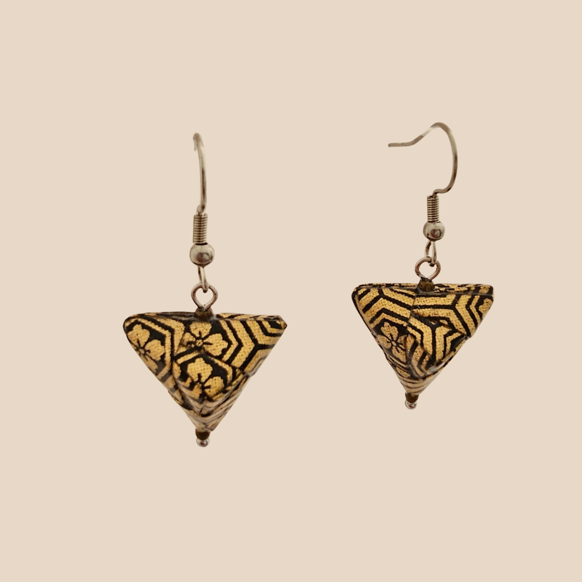 Black and Gold triangle geometric origami earrings with a floral and geometric pattern on a beige background