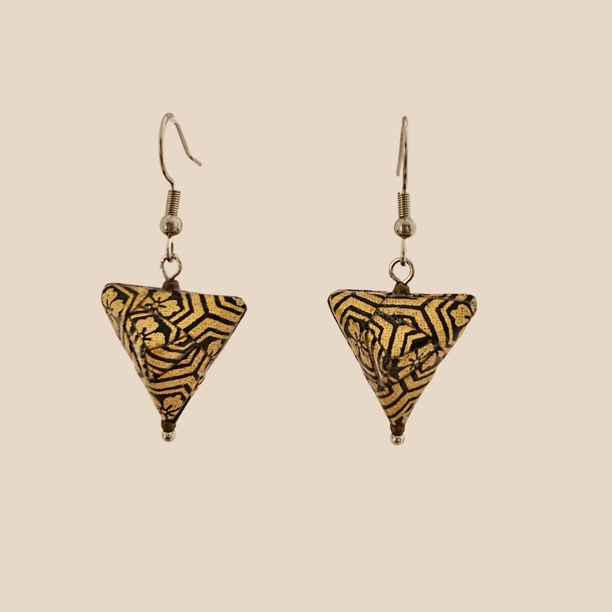 Black and Gold triangle geometric origami earrings with a floral and geometric pattern on a beige background