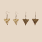 Two paris of white, gold and black triangle geometric origami earrings with a floral and geometric pattern on a beige background