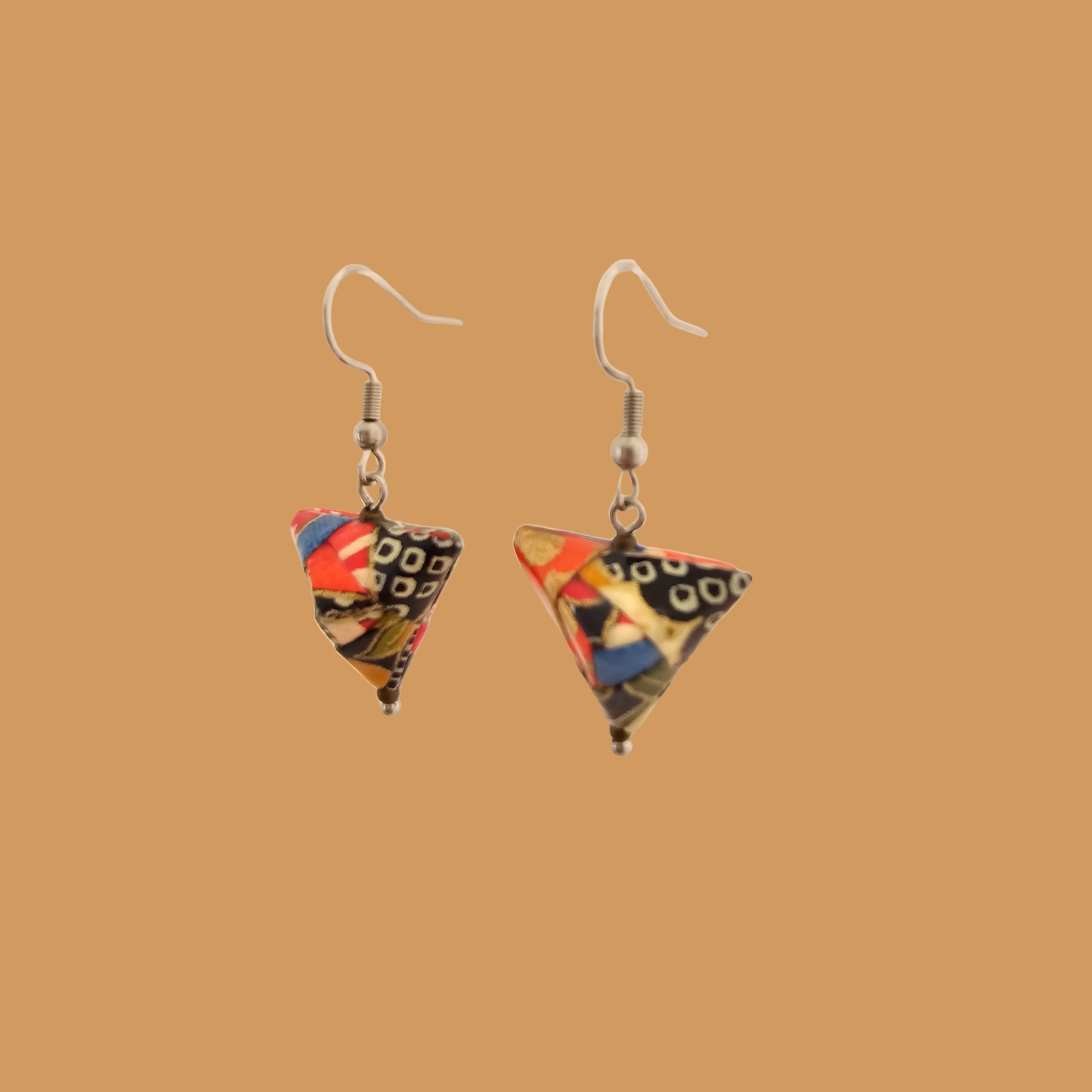 Pair of black, orange, and gold geometric origami earrings with a floral pattern on a beige background.