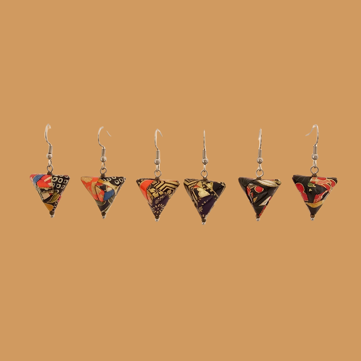 Black and gold geometric origami earrings with a floral pattern on a beige background.