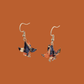 A pair of blue, purple, orange origami lily earrings with a floral and geometric pattern on an orange background