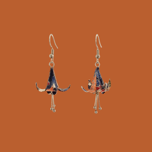 A pair of blue, purple, orange origami lily earrings with a floral and geometric pattern on an orange background