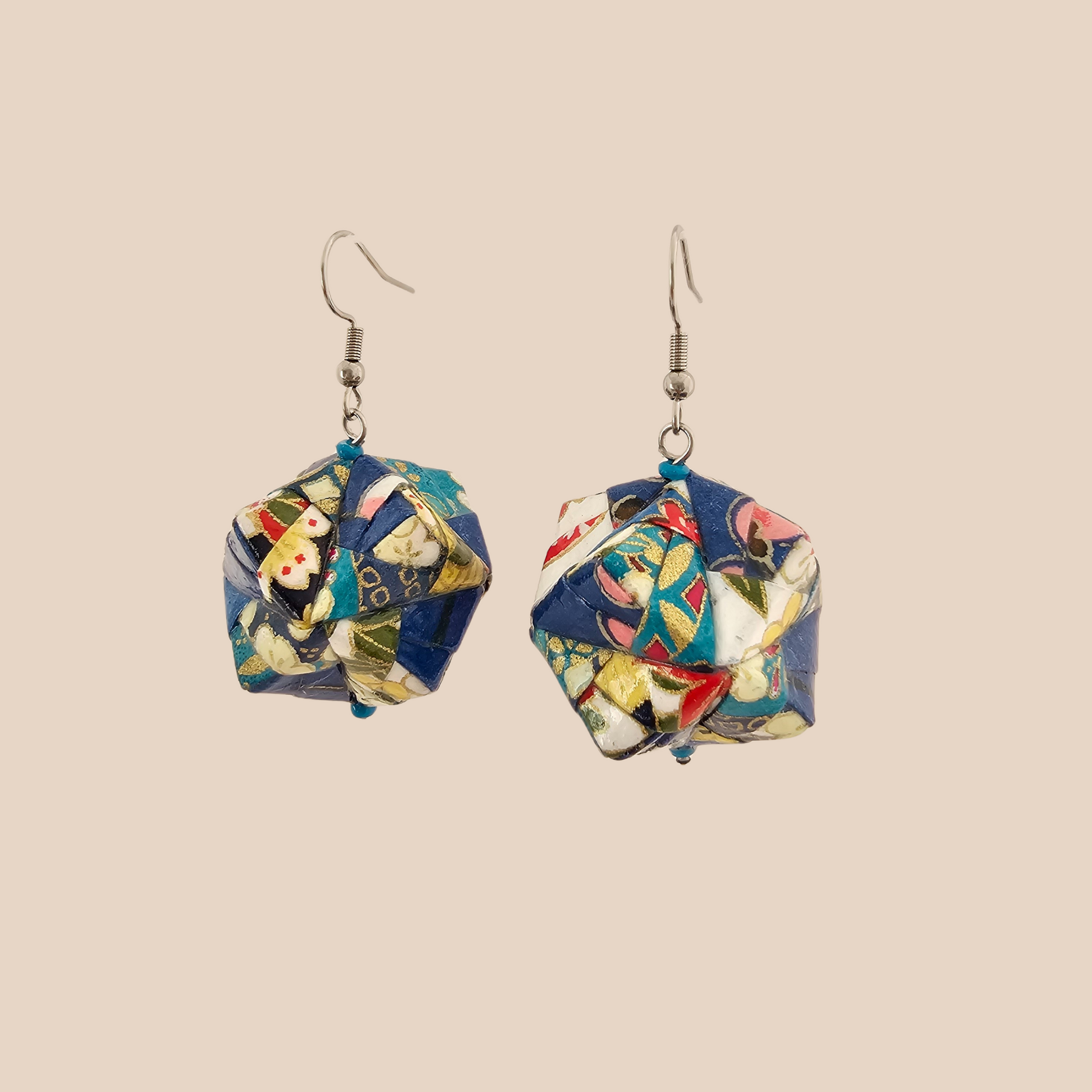 Pair of blue, white, and pink geometric origami earrings with a floral pattern on a beige background.
