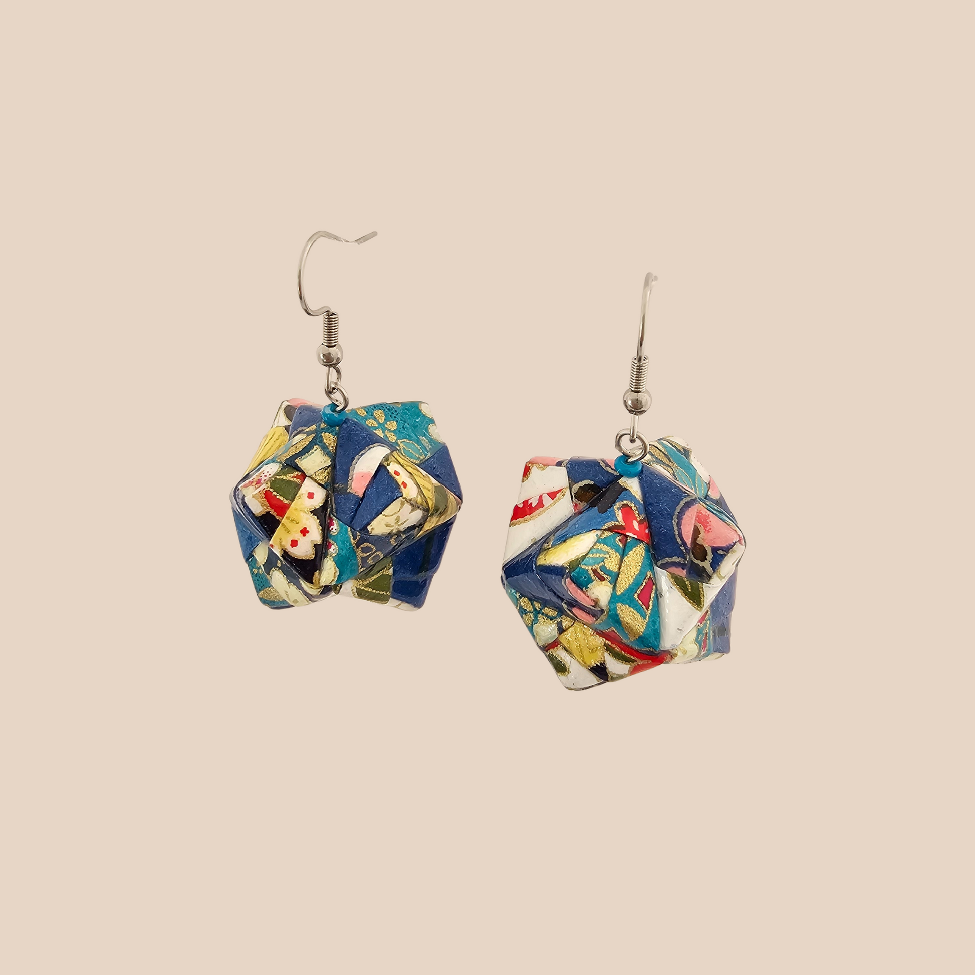 Pair of blue, white, and pink geometric origami earrings with a floral pattern on a beige background.