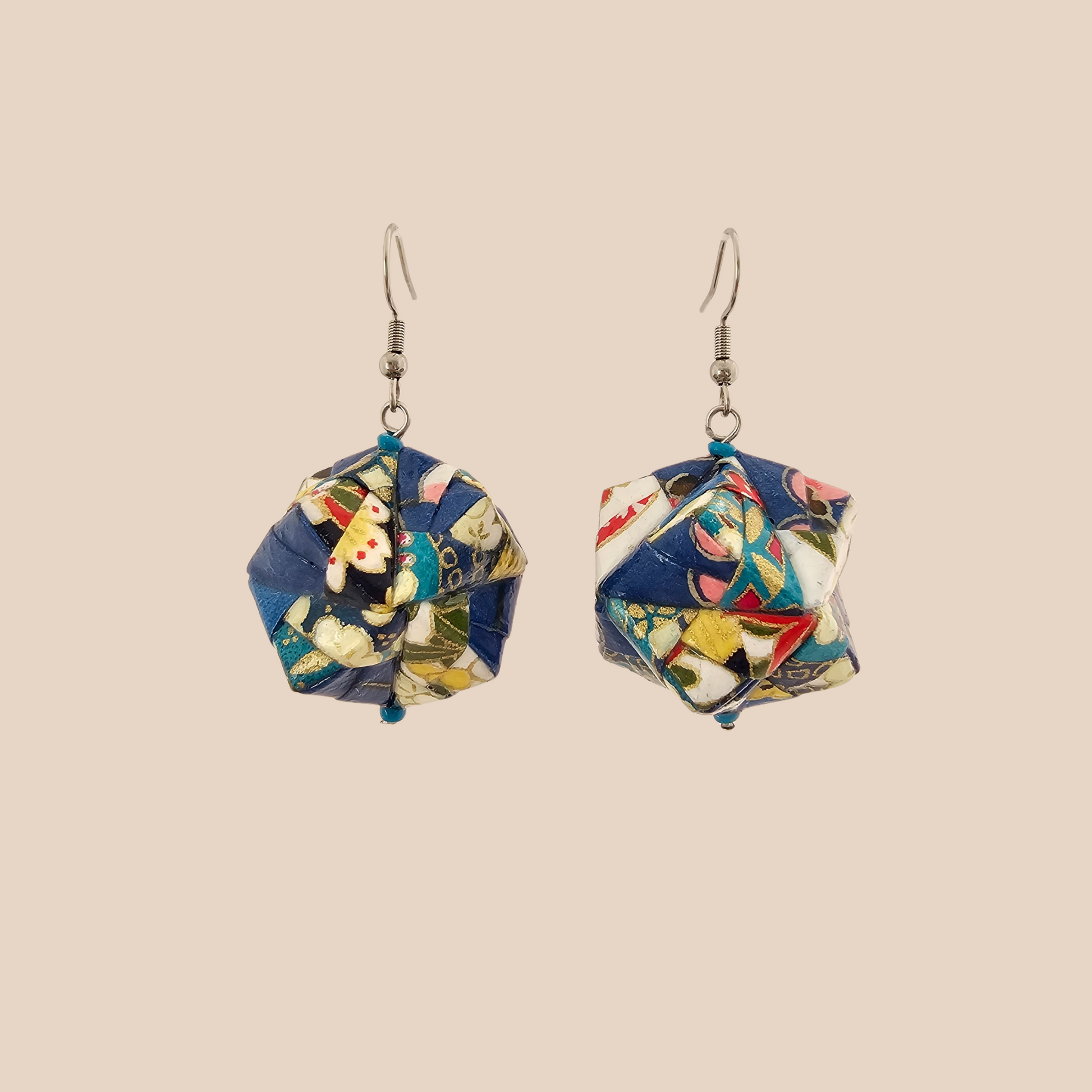 Pair of blue, white, and pink geometric origami earrings with a floral pattern on a beige background.
