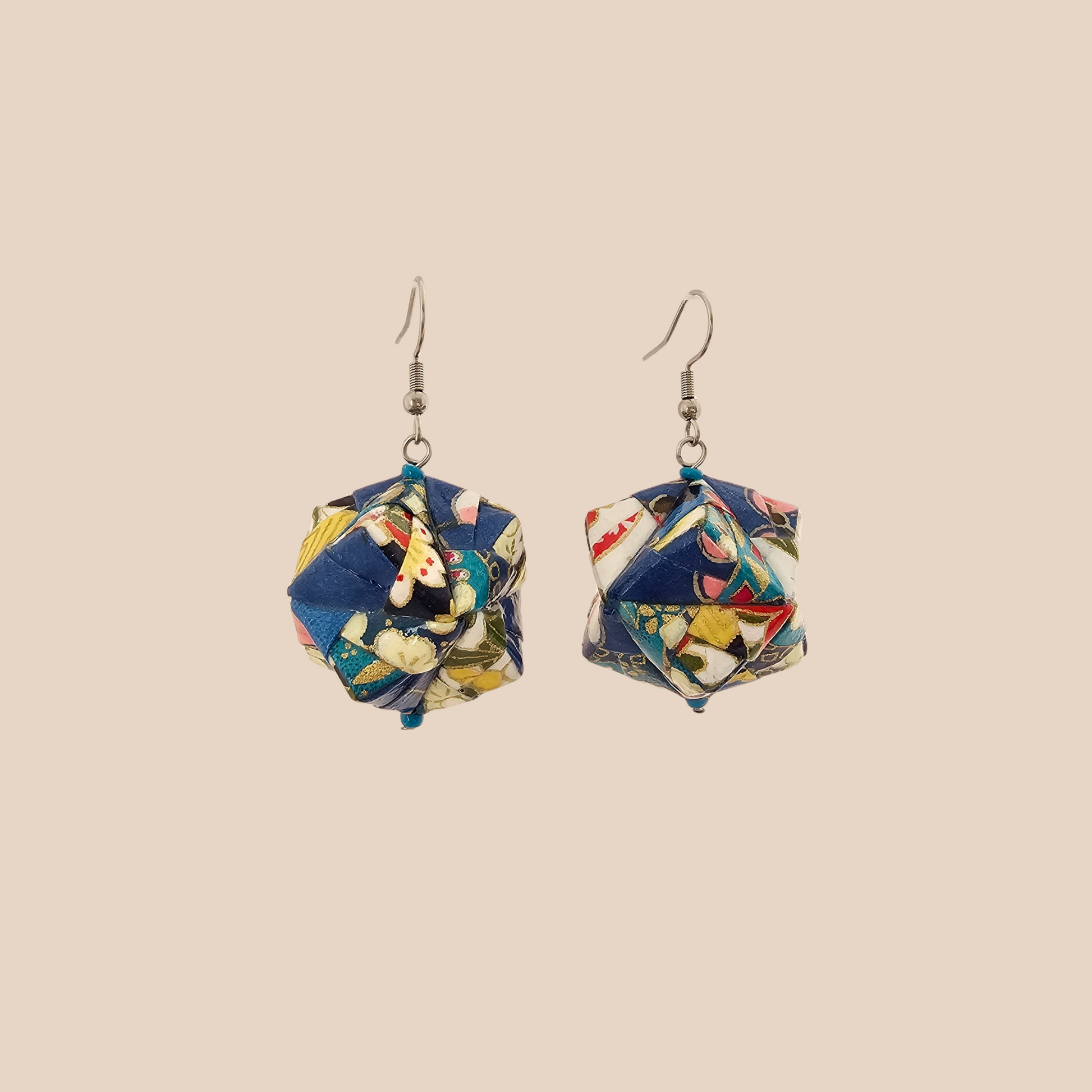 Pair of blue, white, and pink geometric origami earrings with a floral pattern on a beige background.