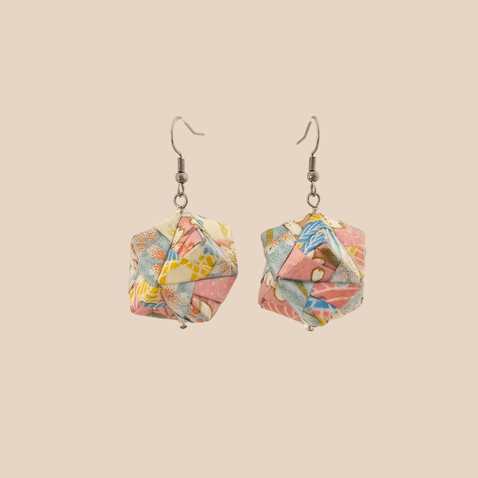 Pair of black and gold geometric origami earrings with a floral pattern on a beige background.