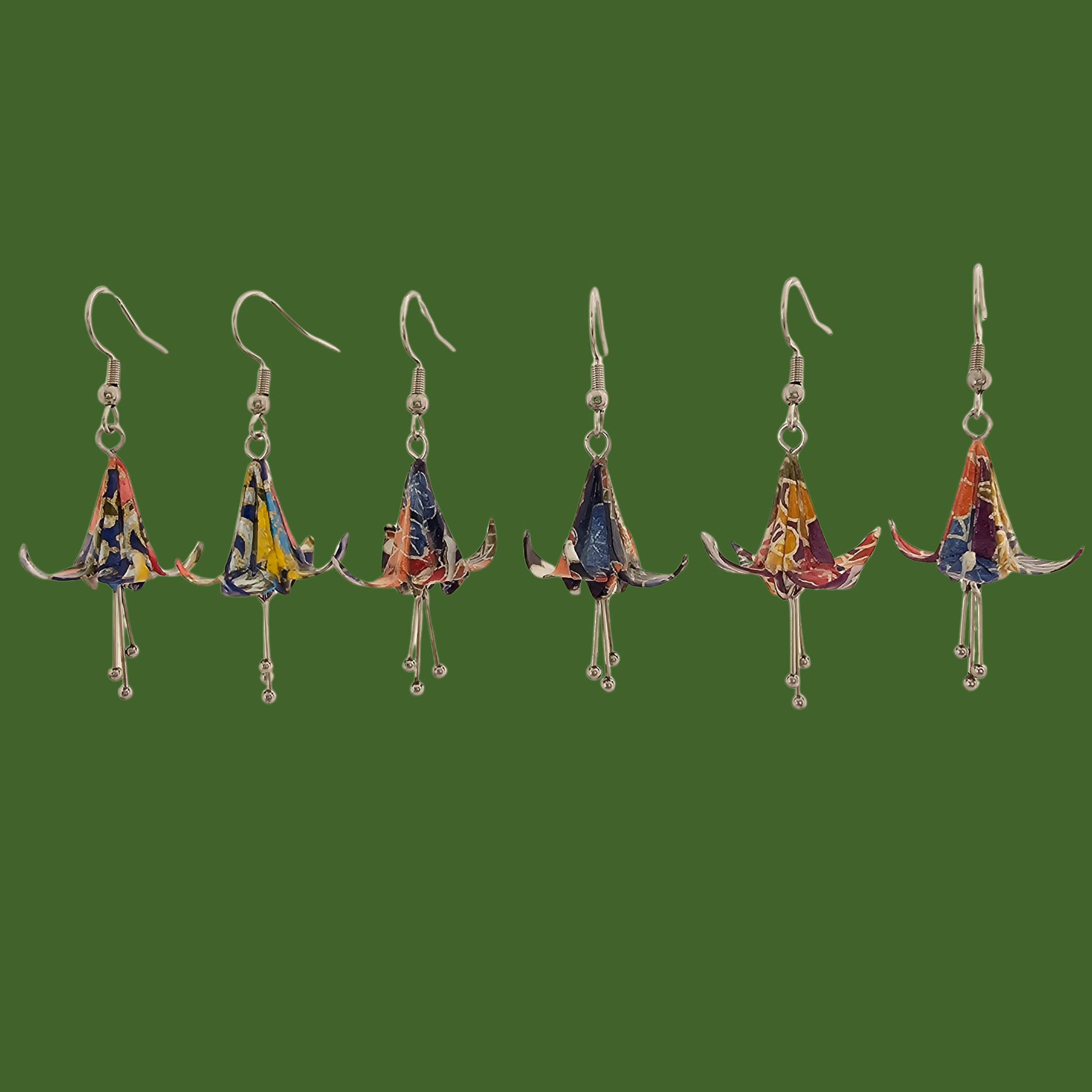 Three pairs of blue and purple origami lily earrings with a floral and geometric pattern on a beige background