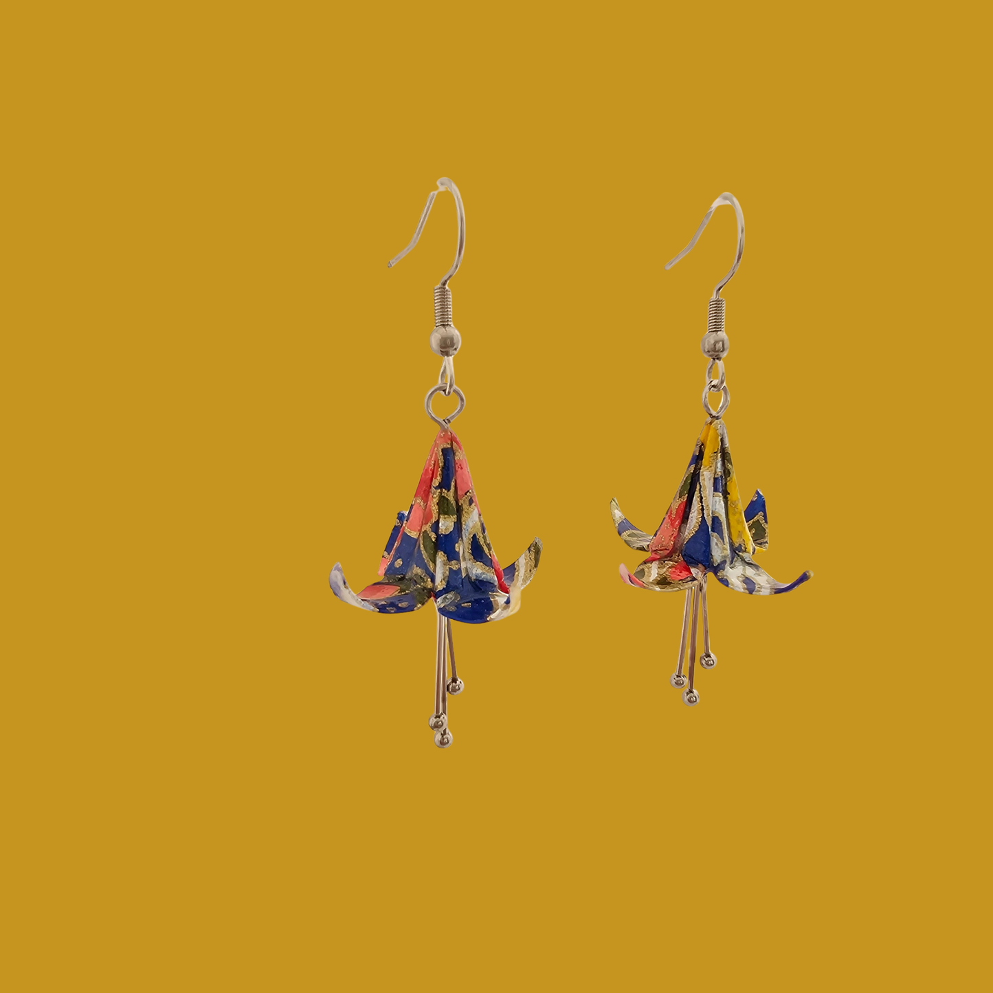 A pair of blue origami lily earrings with a floral and geometric pattern on a yellow background