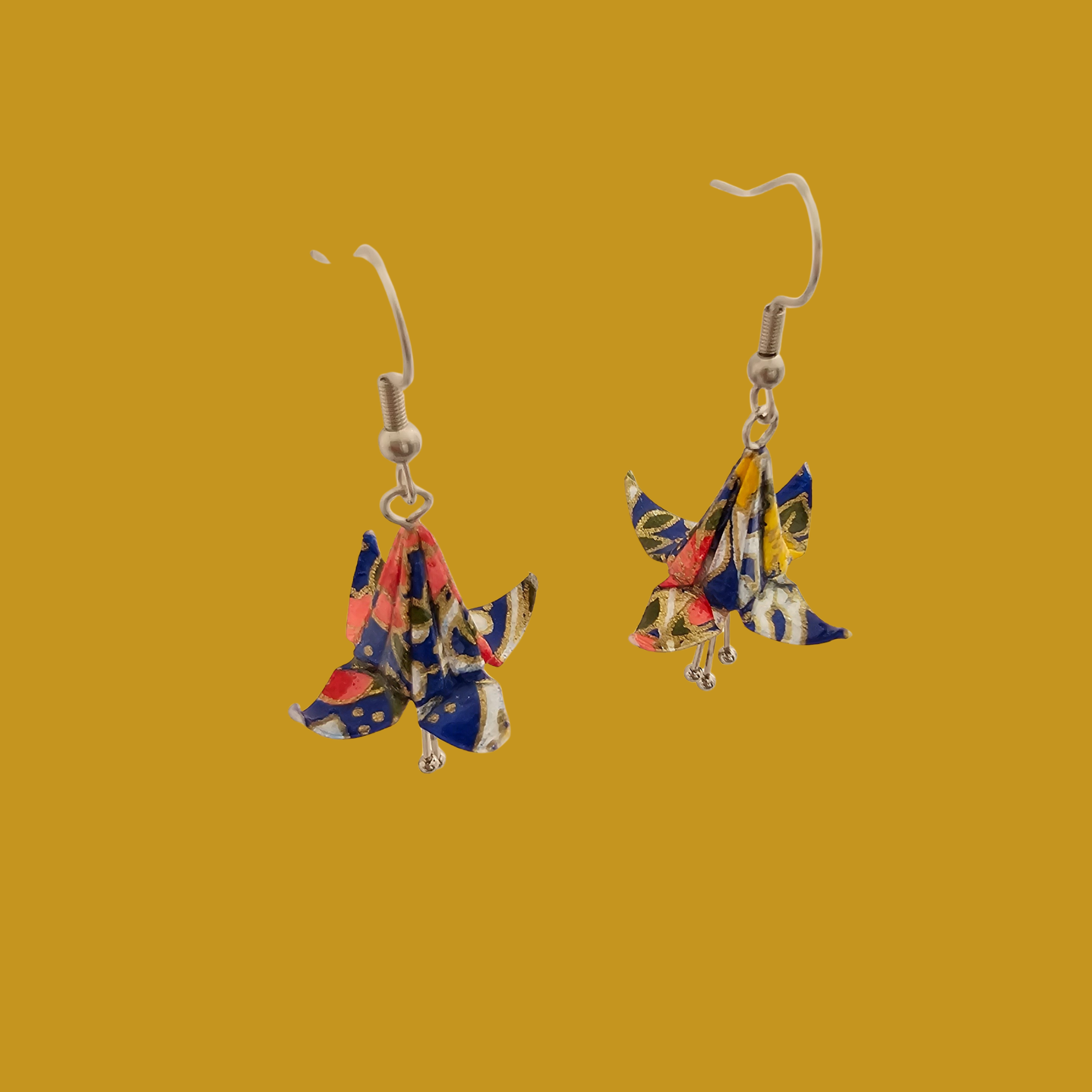 A pair of blue origami lily earrings with a floral and geometric pattern on a yellow background