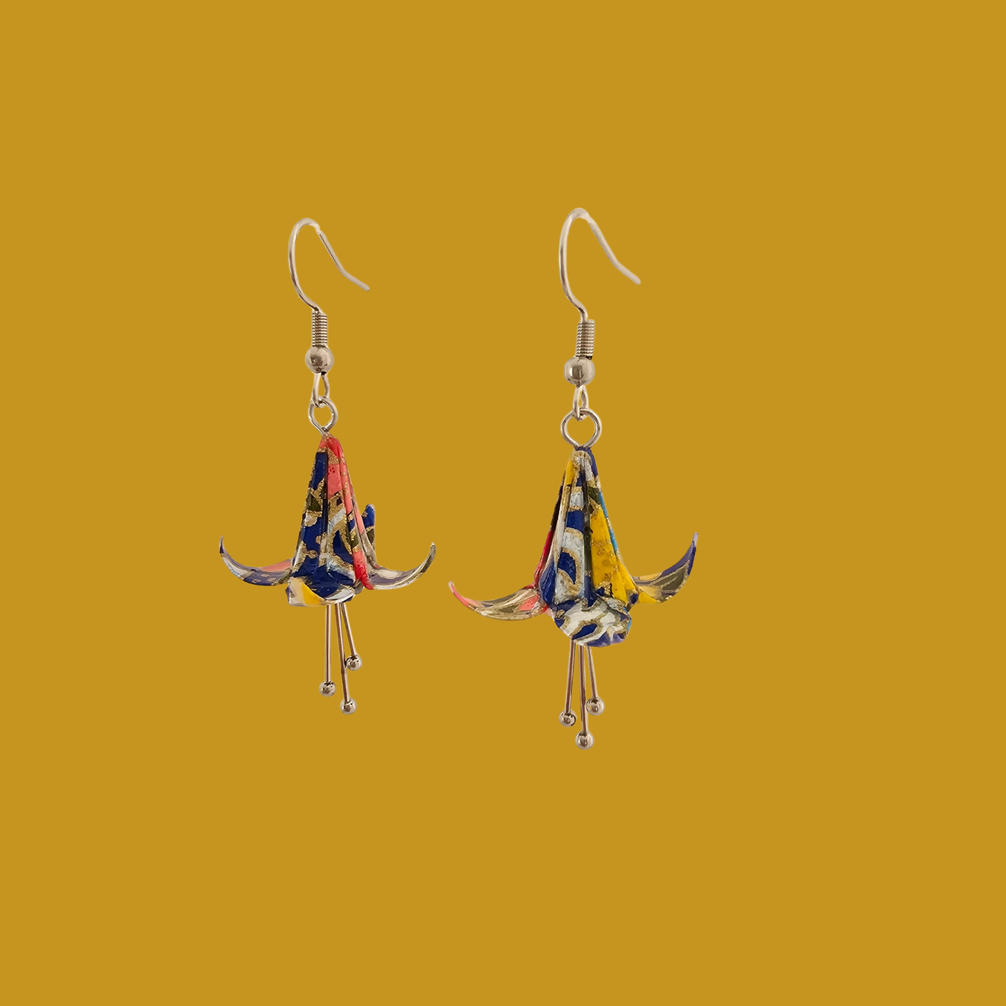 A pair of blue origami lily earrings with a floral and geometric pattern on a yellow background