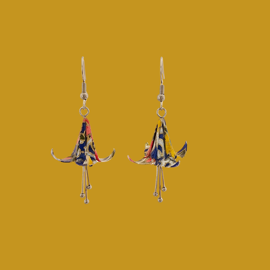 A pair of blue origami lily earrings with a floral and geometric pattern on a yellow background