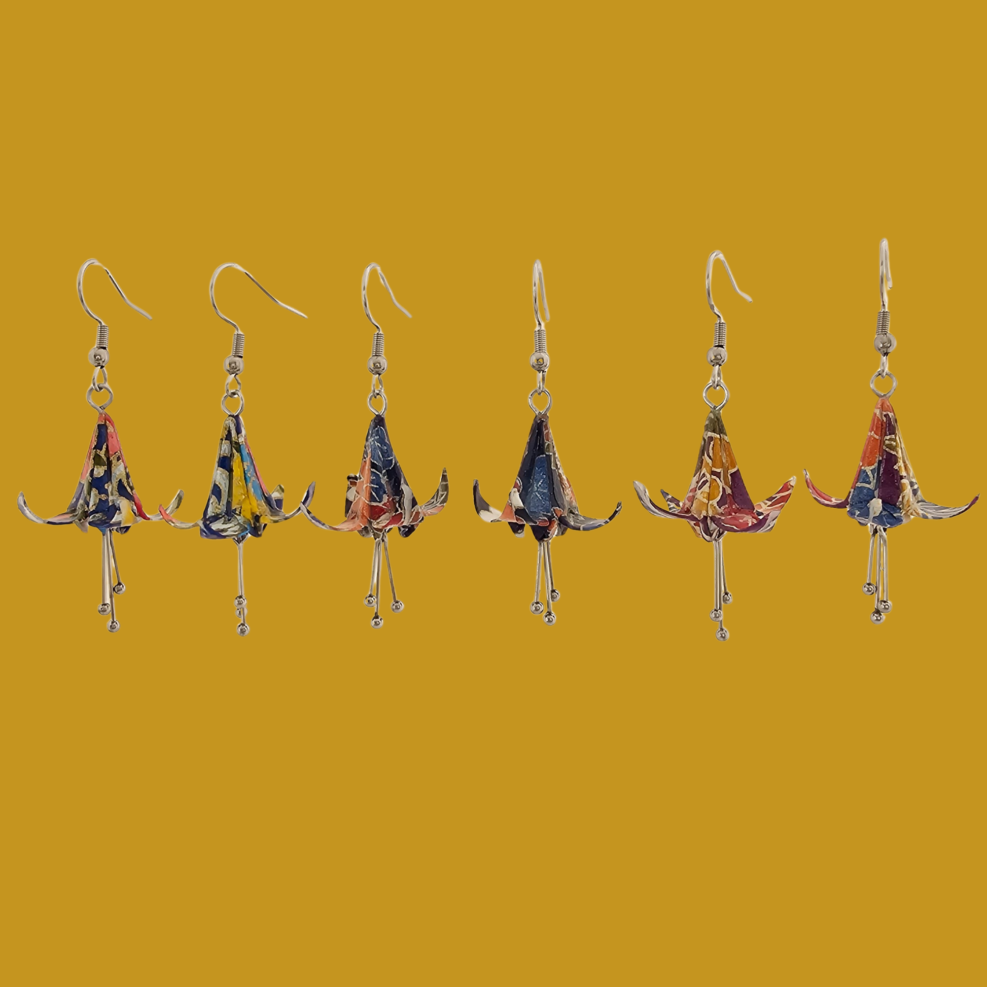 A pair of blue origami lily earrings with a floral and geometric pattern on a yellow background
