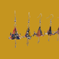 A pair of blue origami lily earrings with a floral and geometric pattern on a yellow background