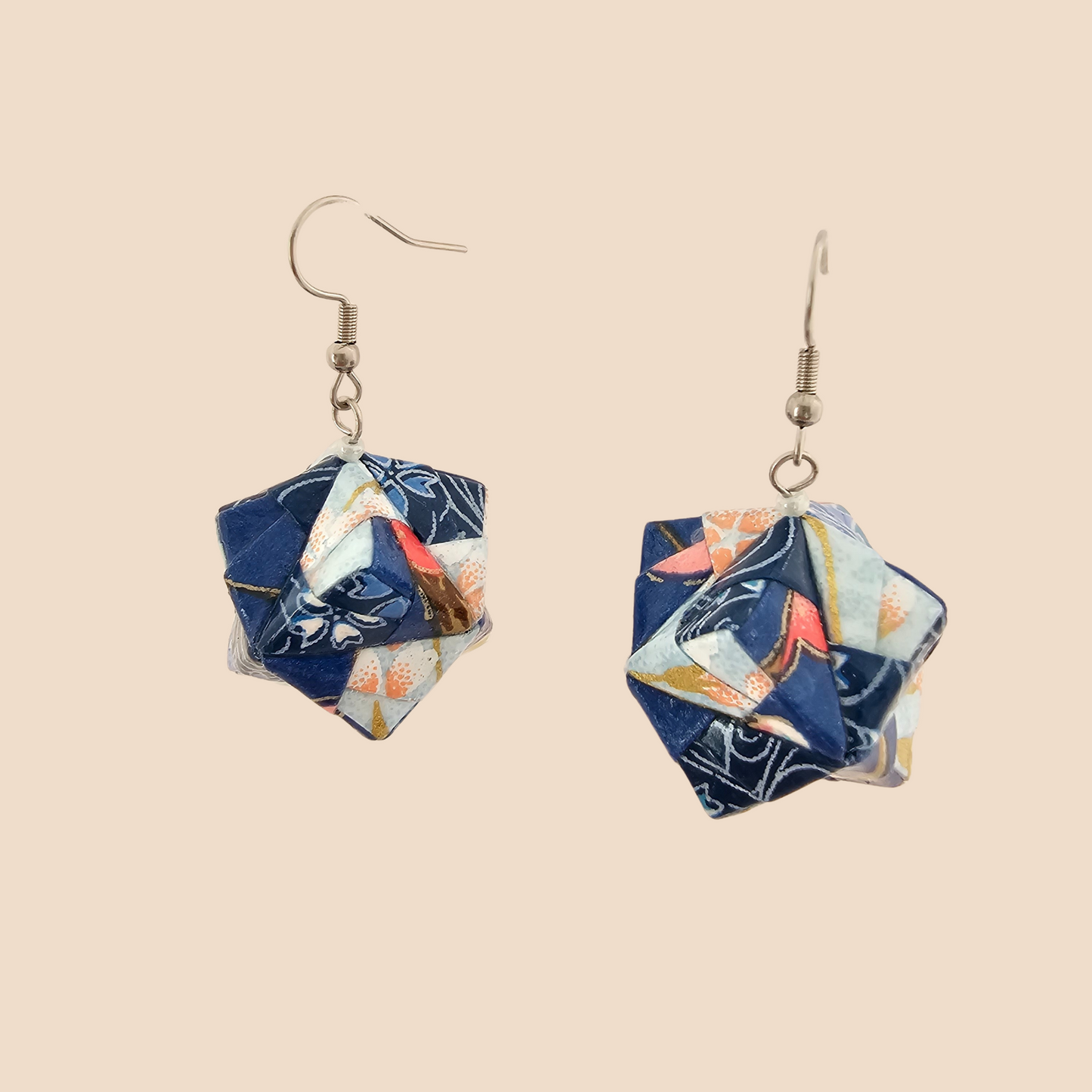 Pair of light blue geometric origami earrings with a floral pattern on a beige background