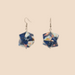 Pair of light blue geometric origami earrings with a floral pattern on a beige background