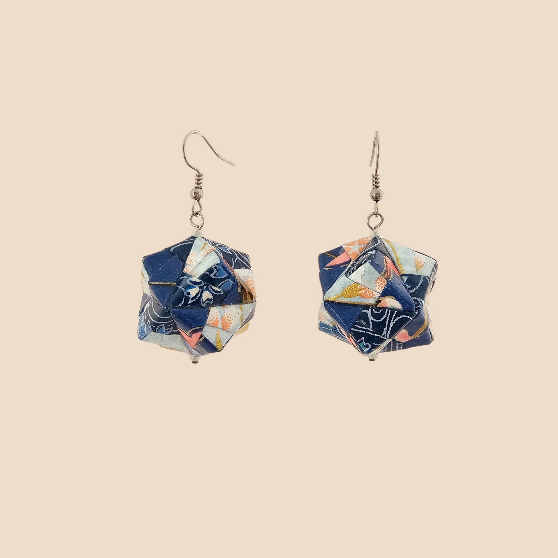 Pair of light blue geometric origami earrings with a floral pattern on a beige background