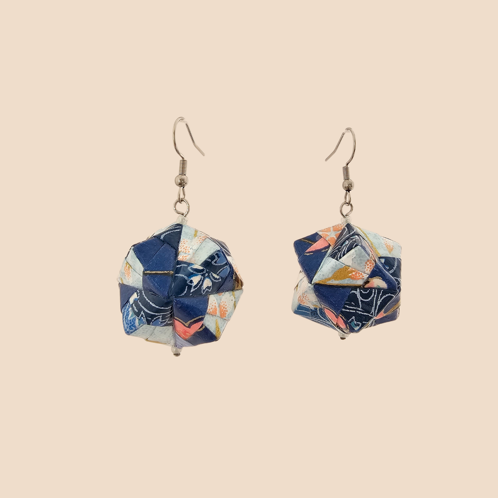 Pair of light blue geometric origami earrings with a floral pattern on a beige background