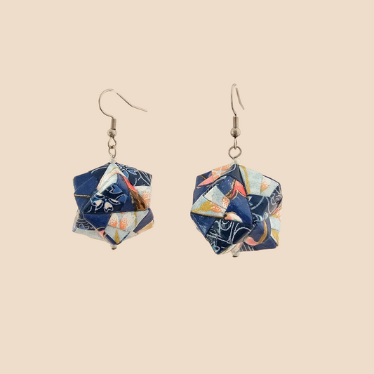 Pair of light blue geometric origami earrings with a floral pattern on a beige background