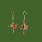 A pair of blue, purple, yellow origami lily earrings with a floral and geometric pattern on a green background