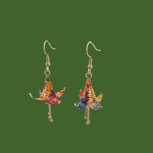A pair of blue, purple, yellow origami lily earrings with a floral and geometric pattern on a green background