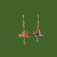 A pair of blue, purple, yellow origami lily earrings with a floral and geometric pattern on a green background