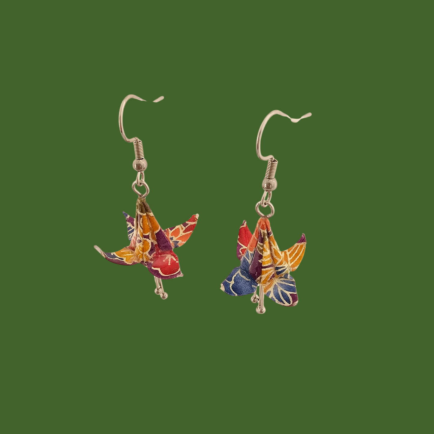 A pair of blue, purple, yellow origami lily earrings with a floral and geometric pattern on a green background