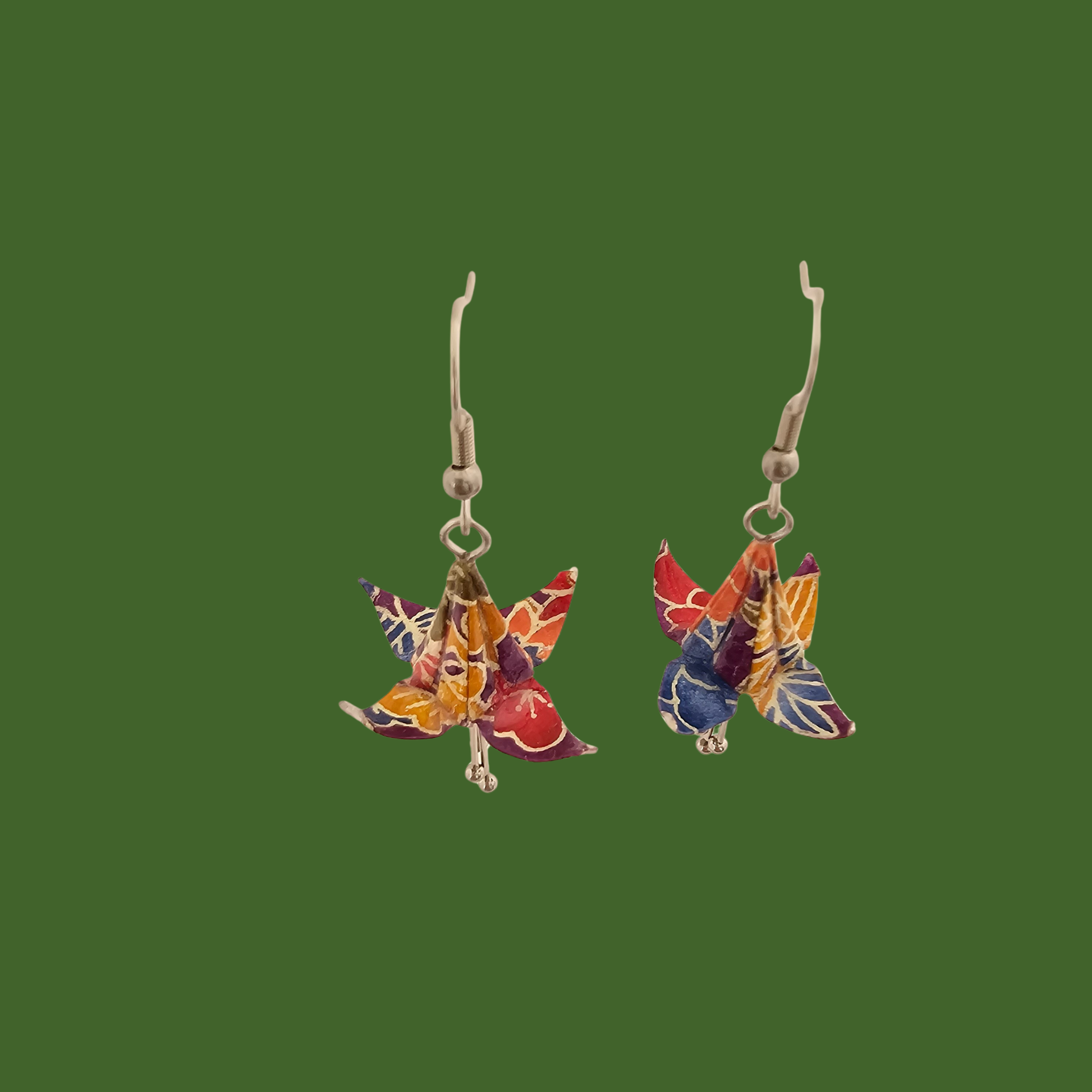 A pair of blue, purple, yellow origami lily earrings with a floral and geometric pattern on a green background