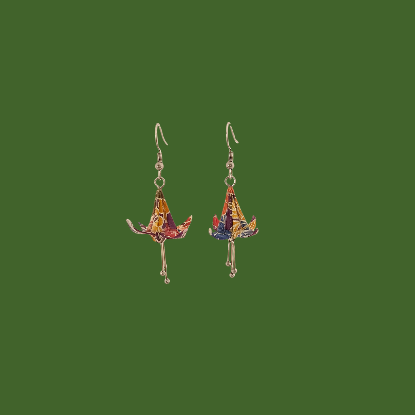 A pair of blue, purple, yellow origami lily earrings with a floral and geometric pattern on a green background