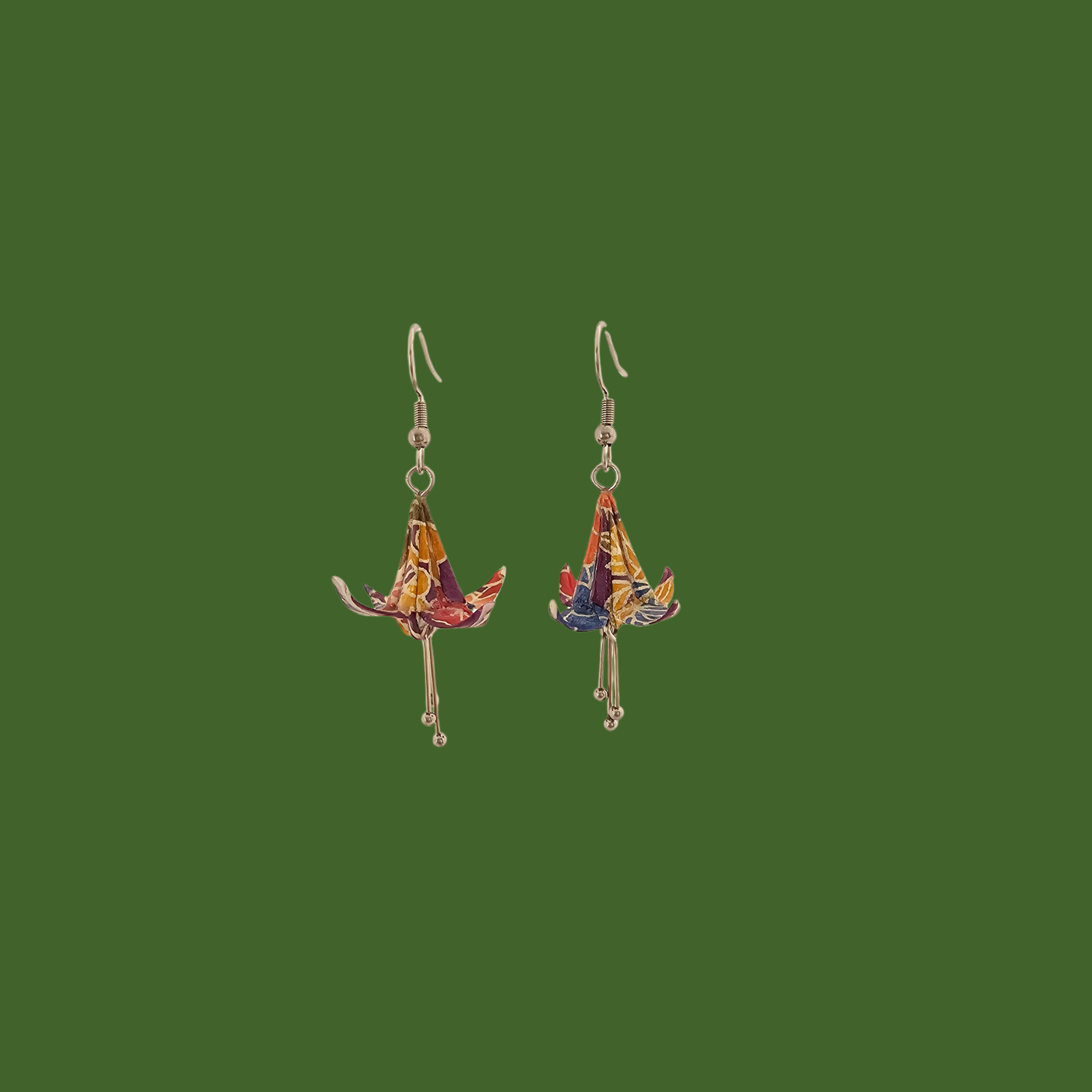 A pair of blue, purple, yellow origami lily earrings with a floral and geometric pattern on a green background