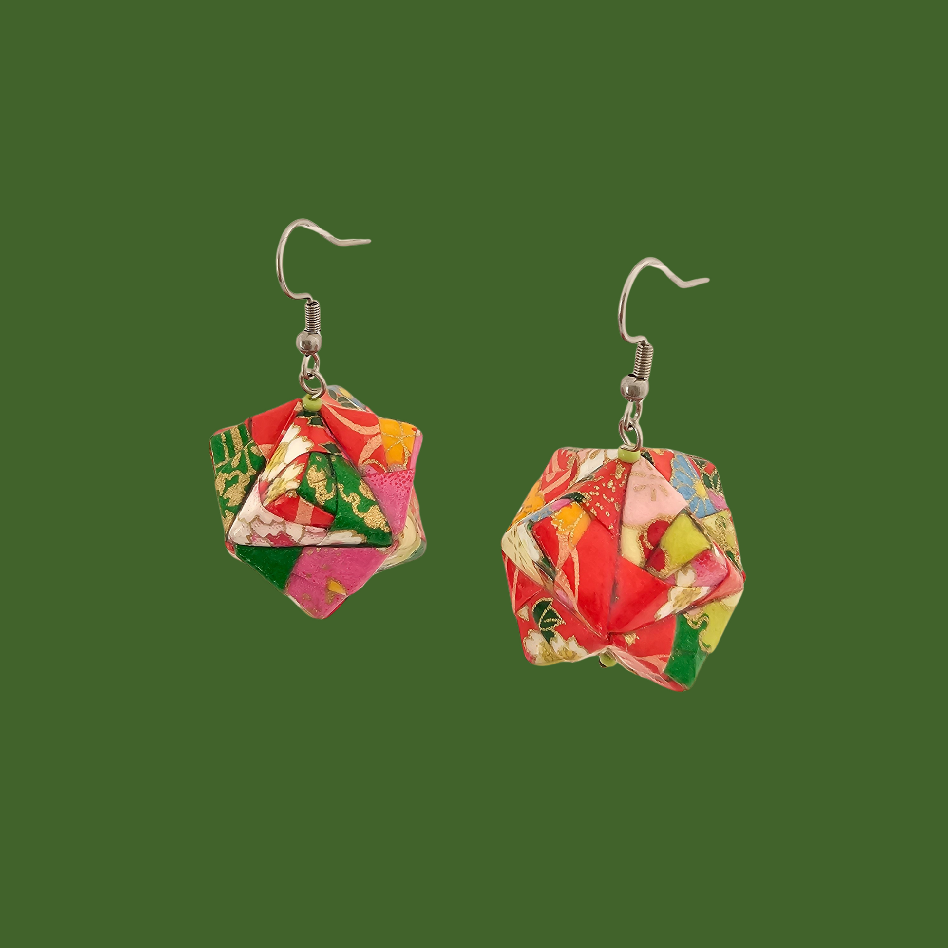 Pair of pink and green geometric origami earrings with a floral pattern on a green background.