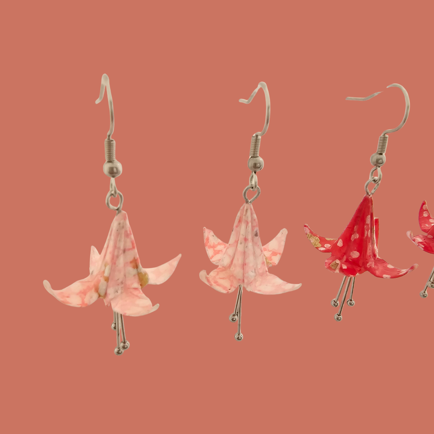 Two Pairs of Pink and red origami lily earrings with a floral and geometric pattern on a beige background