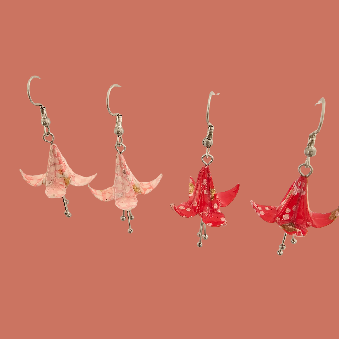 Two Pairs of Pink and red origami lily earrings with a floral and geometric pattern on a beige background