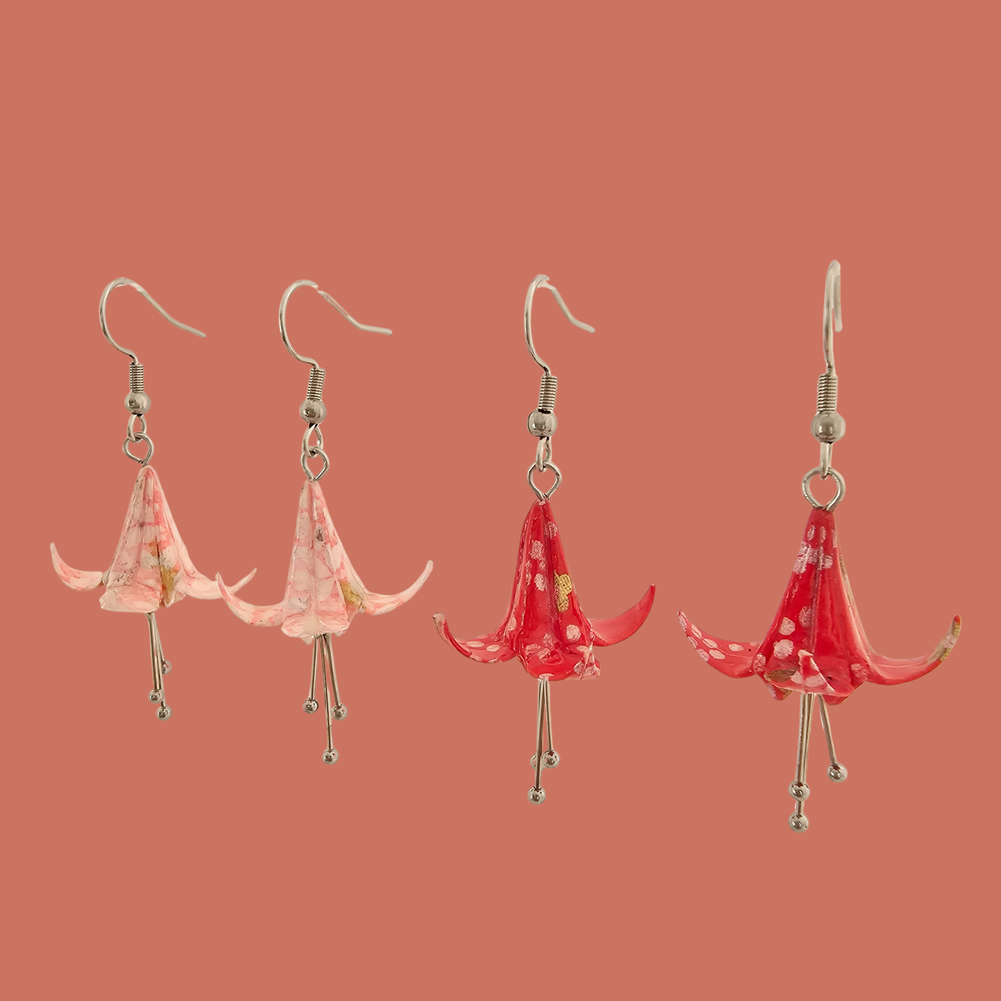 Two Pairs of Pink and red origami lily earrings with a floral and geometric pattern on a beige background