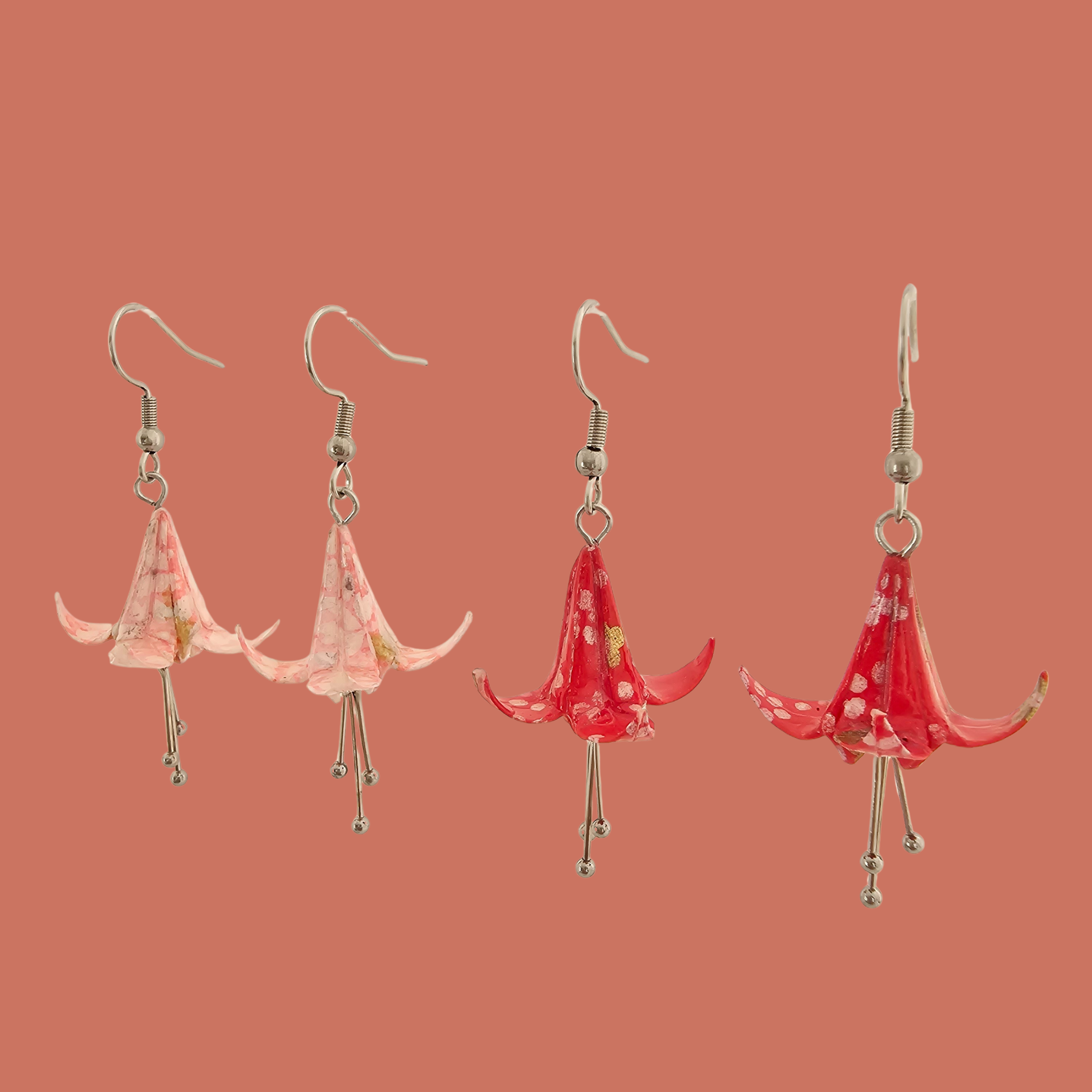 Two Pairs of Pink and red origami lily earrings with a floral and geometric pattern on a beige background