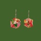 Pair of pink and green geometric origami earrings with a floral pattern on a green background.
