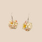 Pair of white geometric origami earrings with a floral pattern on a beige background